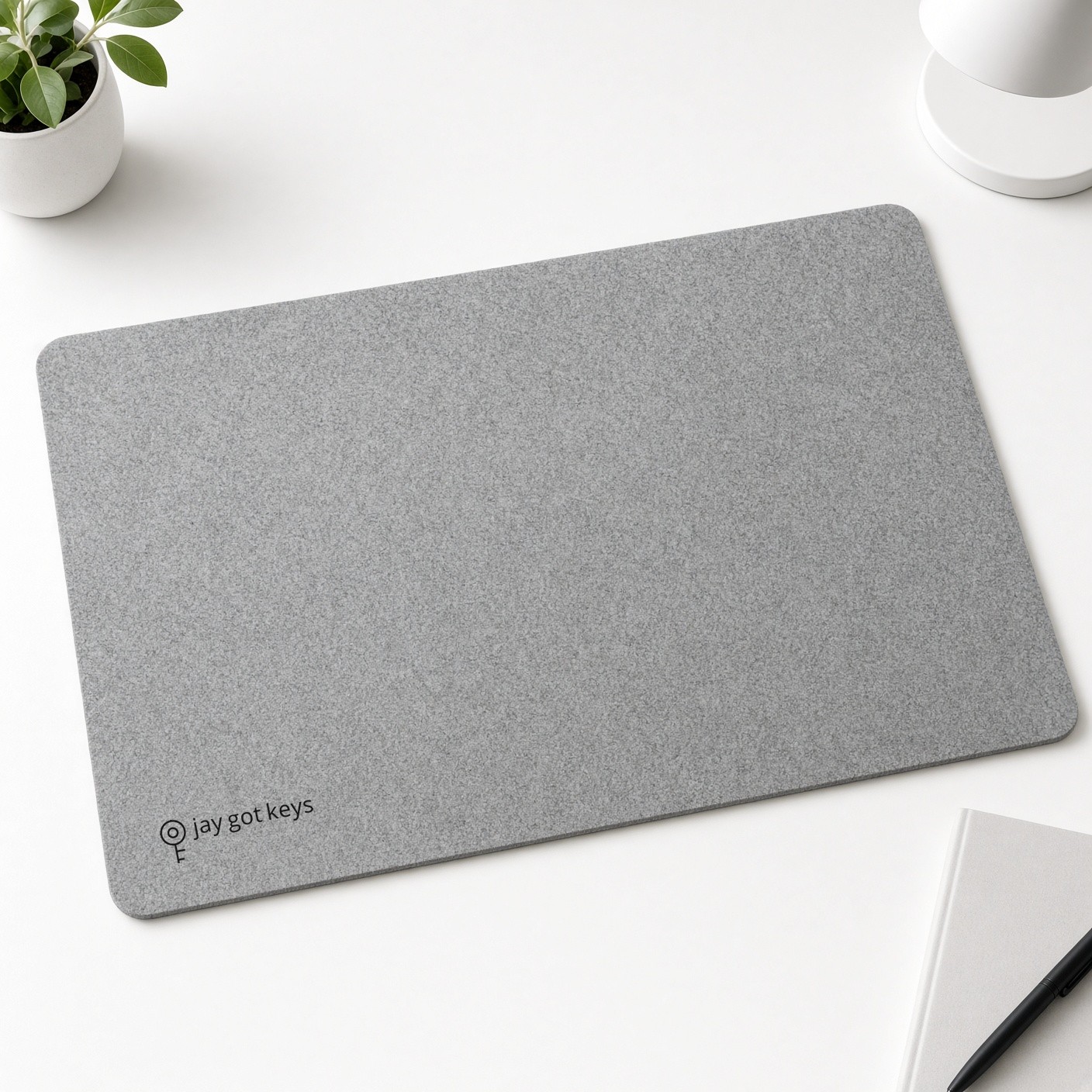Grey desk pad with a small black jay got keys logo